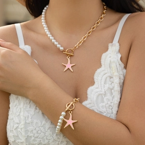 Dettaglio della collana con ciondolo a stella marina e bracciale di perle su pizzo bianco