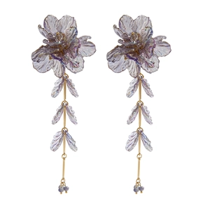 Détail de boucles d'oreilles fleurs en résine lavande avec de franges dorées élégantes