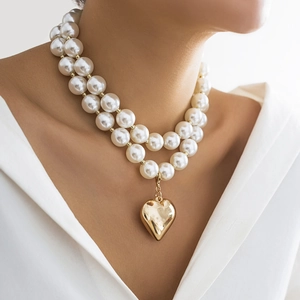 Detail view of double-layer pearl necklace featuring a large golden heart-shaped pendant