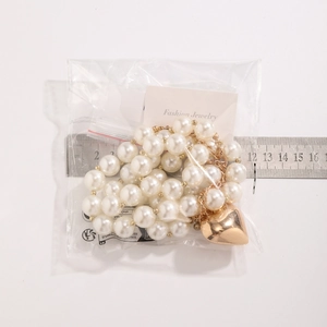 Macro shot of a pearl necklace with golden heart pendant and ruler for size scale