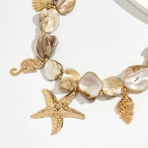 Dettaglio della collana di conchiglie barocche con ciondoli dorati a forma di cavalluccio