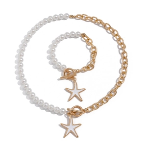 Dettaglio della collana a catena dorata asimmetrica con perle sintetiche e ciondolo a stella