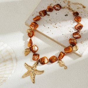 Dettaglio di una collana marina con ciondoli dorati di creature marine e perle marroni