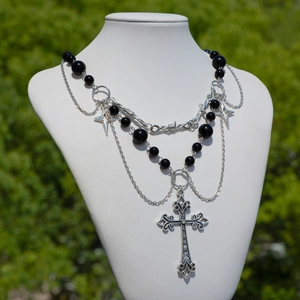 Dettaglio della collana punk gotica con croce d'argento e perle finte nere