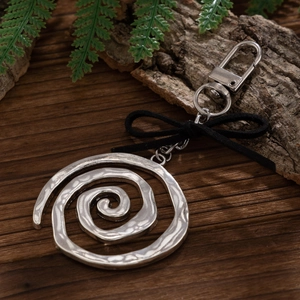 Détail macro d'un porte-clés spirale en métal argenté avec un nœud en ruban noir