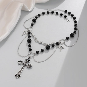 Dettaglio di una collana gotica multistrato con ciondolo a croce, perle nere e stelle