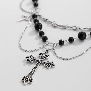 Dettaglio della collana gotica multistrato con perline, catena d'argento e ciondolo a croce