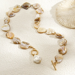 Dettaglio della collana di conchiglie con perle dorate, chiusura OT e decoro di corallo
