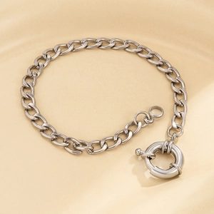 Close-up of a silver metal chain necklace with a large sailor clasp on a ceramic plate