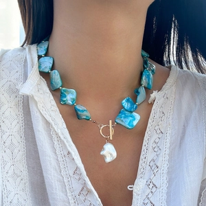 Dettaglio della collana stile oceano con pietre blu e ciondolo di perla barocca bianca