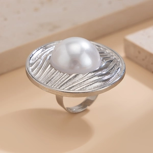 Makroansicht der silbernen Metallstruktur und der großen weißen Kunstperle am Ring