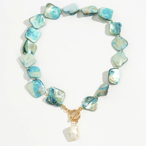 Dettaglio collana in conchiglia blu con chiusura a T dorata e ciondolo in perla barocca