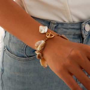 Dettaglio di un bracciale dorato con chiusura OT e perle barocche naturali
