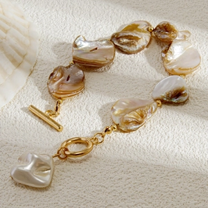 Dettaglio di bracciale in conchiglia naturale con chiusura a T oro e ciondolo a cuore