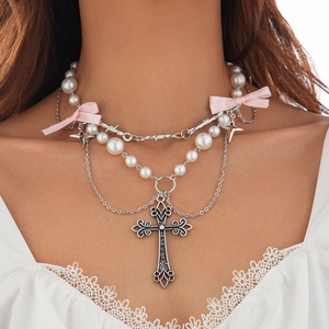 Dettaglio della collana punk a strati con croce d'argento, perle e fiocco rosa