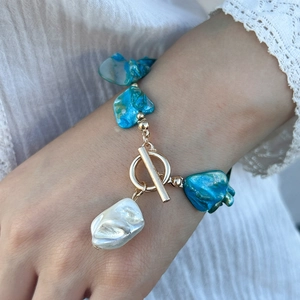 Detail of beaded sea style necklace with deep blue stones and a white baroque pearl pendant