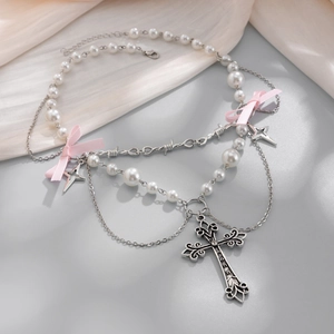Dettaglio collana di perle multistrato con ciondolo a croce e fiocco rosa
