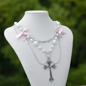 Dettaglio della collana croce gotica con fiocco rosa e catene di perle stratificate