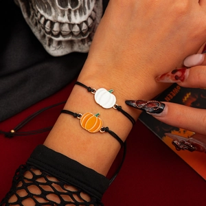 Detail von verstellbaren Halloween-Armbändern mit orangefarbenen und weißen Kürbis-Anhängern