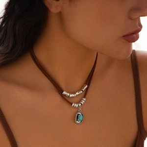 Detail of bohemian layered necklace with turquoise oval pendant and silver tube beads