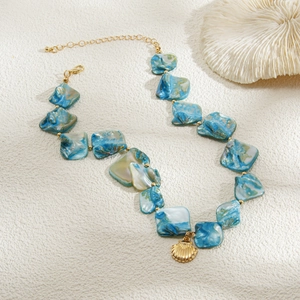 Dettaglio della collana oceanica con perline blu perlate e ciondolo a conchiglia dorato