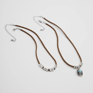 Dettaglio di collane boho con pendente turchese e perle d'argento su cordini marroni