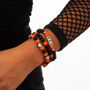 Detalle de pulseras de Halloween con dijes de fantasmas y cuentas con letras BOO en la muñeca