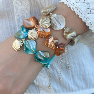 Dettaglio di bracciali a strati con perle di conchiglia e ciondoli a stella marina dorati