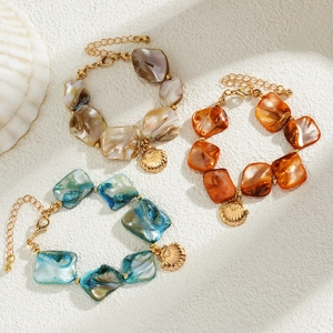 Detail of seashell charm bracelets in pearl white, amber orange, and turquoise blue