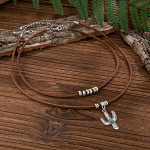 Detail of bohemian necklace featuring cactus pendant with turquoise and brown velvet cords
