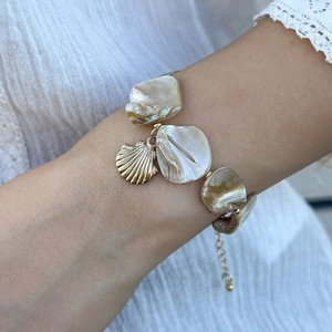 Dettaglio ravvicinato di un bracciale con ciondolo a conchiglia sul polso di una modella