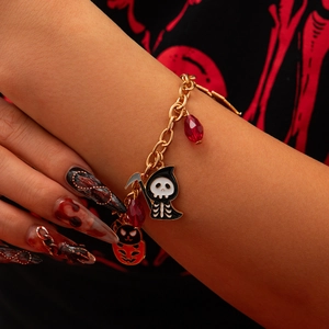 Bracciale di Halloween con ciondoli a forma di scheletro e zucca su polso di modella