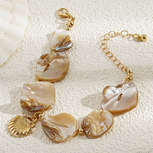 Dettaglio macro del bracciale con frammenti di conchiglia e ciondolo stella marina d'oro