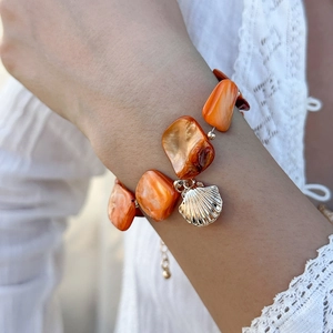 Dettaglio della collana bohémien con perline arancioni e ciondolo a conchiglia dorata
