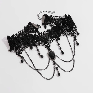 Macro shot of gothic black lace choker with oval gemstone and metal tassel details