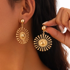 Détail de boucles d'oreilles soleil dorées surdimensionnées avec sphères en métal