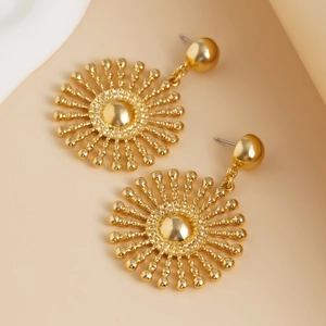 Détail macro de boucles d'oreilles soleil dorées avec rayons métalliques polis et perles