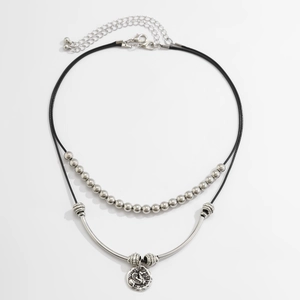 Dettaglio di una collana a due strati con perline d'argento e ciondolo vintage a rilievo