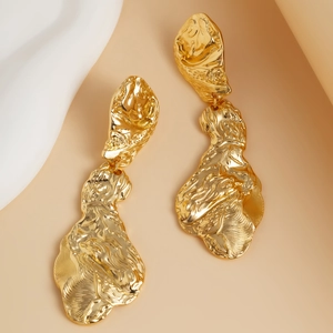 Vue macro de boucles d'oreilles dorées avec texture lave et fini martelé irrégulier