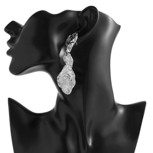 Détail de boucles d'oreilles argentées avec texture de lave sur mannequin noir