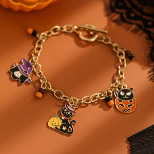 Dettaglio del bracciale di Halloween con ciondoli smaltati a forma di gatto e zucca dorati