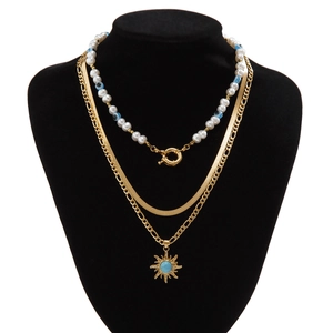 Details einer mehrlagigen Goldkette mit Perlen, Evil-Eye-Perlen und Sonnenanhänger am Modell