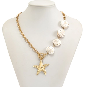 Detail einer klobigen Goldkette mit weißen Muscheln und einem strukturierten Seestern-Anhänger