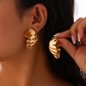 Gros plan de boucles d'oreilles dorées plissées irrégulières avec finition miroir poli