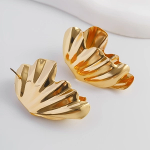 Détail macro de boucles d'oreilles dorées irrégulières avec une finition métallique