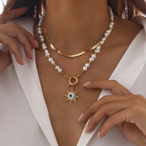 Detail der zweilagigen Gold-Schlangenkette und Perlenhalskette mit Sonnenanhänger