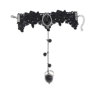 Detail of gothic black lace finger bracelet with dark gemstone and embroidery