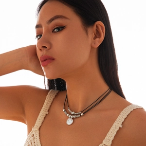 Double-layer choker necklace featuring black cord, silver beads and shell pendant on model