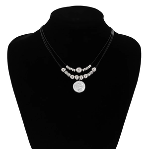 Detail of layered black rope necklace with silver beads and flat white shell pendant