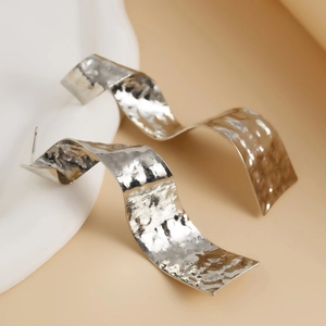 Détail macro de boucles d'oreilles ruban argenté avec texture métal martelé
